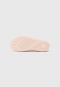 Lichtroze schoenzool met een gestructureerd oppervlak, met een voetvormig ontwerp, cirkelvormige accenten en verhoogde patronen voor grip.