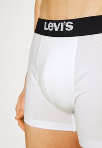 Fehér pamut boxer alsónadrág fekete elasztikus derékpánttal, amelyen fehér "Levi's" logó található. Simaság és testhezálló fazon jellemzi.
