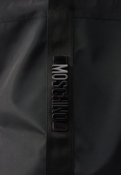 Μαύρο ύφασμα με κάθετο μαύρο ιμάντα που φέρει ανάγλυφα μαύρα γράμματα που σχηματίζουν τη λέξη "MOSCHINO" στο κέντρο.