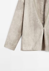 Veste à manches courtes, gris clair, à texture douce, avec un col en V profond et une ouverture avant élégante, agrémentée d'un bord contrastant.