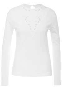 Camicia bianca a maniche lunghe con scollatura ondulata, caratterizzata da dettagli floreali ricamati e una piccola apertura a goccia sul retro.