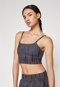 Top cropped cinza com textura ribbed vertical, alças finas e decote arredondado. Combinado com calções escuros de cintura elástica.