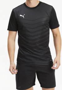 Svart sporttröja i lätt tyg med ett texturerat, randigt mönster. Kortärmad med rund halsringning, kombinerad med svarta shorts.