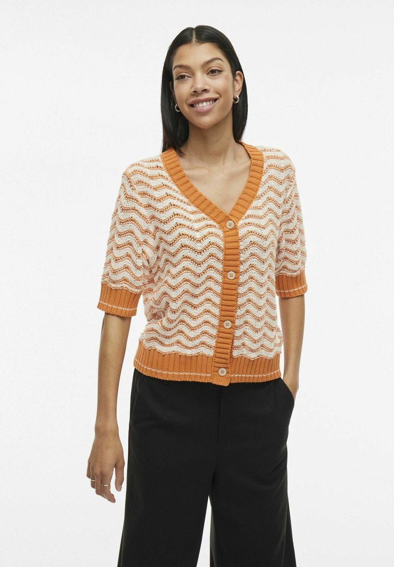 Cardigan intrecciato con motivo a zig zag arancione e bianco, scollatura a V, maniche corte, orlo e polsini a costine e chiusura frontale con bottoni.