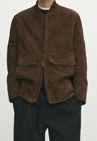 Bruine suède bomberjack met ritssluiting, geribde kraag en twee opgestikte voorzakken. Het ontwerp heeft een losse pasvorm en een gladde textuur.