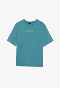 Camiseta de algodón en color teal, de mangas cortas y cuello redondo, que presenta un gráfico central de una estrella y lunas crecientes en blanco. Diseño suave y casual.