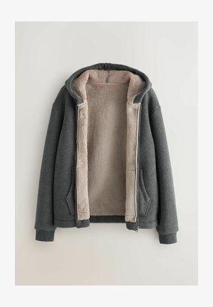 Hallitanud, kaelarihmaga kapuutsiga heledates beezitoonis sherpa voodriga hall zip-up pusa, millel on kaks esimest taskut ning soonikkoes varrukad ja alumine äär.