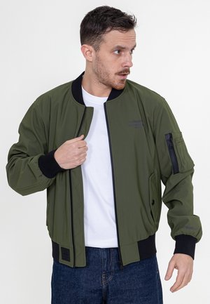 Olivgrüne Bomberjacke mit Reißverschluss, geripptem Kragen und Bündchen, Fronttaschen und einer kleinen Reißverschlusstasche am Ärmel.