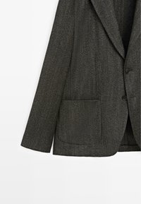 Blazer grigio a spina di pesce con rever a incavo, chiusura frontale con un solo bottone e tasca applicata. Presenta un tessuto strutturato e una vestibilità rilassata.