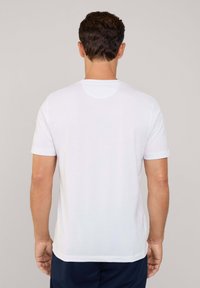 Witte korte mouwen t-shirt van katoen, met een ronde halslijn en een eenvoudig ontwerp, vanuit de achterkant bekeken. Glad textuur.