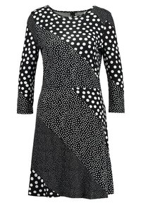 Robe noire ornée de motifs variés de pois blancs. Elle possède un col rond et des manches longues, avec une forme évasée.