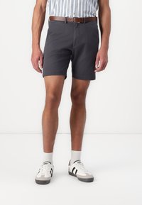 Dark gray shorts with a classic fit, paired with a striped shirt, brown belt, and white sneakers featuring black accents.