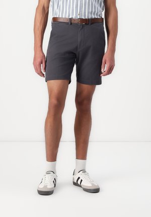 Dark gray shorts with a classic fit, paired with a striped shirt, brown belt, and white sneakers featuring black accents.