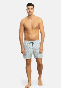 Bañadores con un fondo azul claro, presentando un patrón de gotas de agua multicolores. Fabricados con tejido transpirable; cinturilla elástica con cordón.