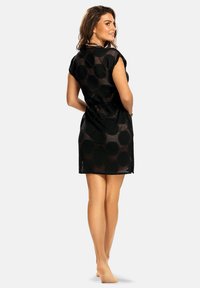 Czarna siatkowana sukienka o luźnym kroju, krótkich rękawach, okrągłym dekolcie i wzorzystej teksturze z dużymi okrągłymi motywami.