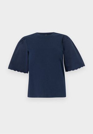 Blouse bleu marine à manches courtes bouffantes avec bords festonnés sur fond uni.