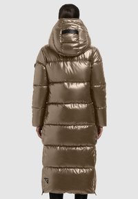 Long puffer coat in metallic bronze, featuring a hood, quilted design, and a side zipper with a logo patch near the hem. Smooth texture.