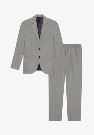 Lichtgrijs pak bestaande uit een blazer en joggingsbroek met drawstring. De blazer heeft een sluiting met twee knopen en een notch kraag.