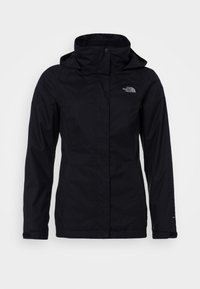 Veste imperméable noire avec un col haut et une capuche réglable. Dispose de poches latérales et d'un logo subtil sur la poitrine. Texture du tissu lisse.