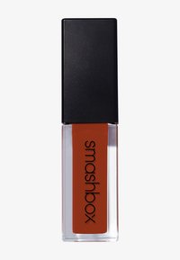 Flytande läppstift med en rektangulär svart kork och genomskinlig behållare. Innehåller en djup orange-röd nyans märkt "smashbox."