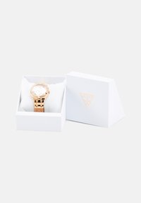 Orologio color oro rosa con quadrante rotondo e accenti di cristallo, posizionato su un cuscino bianco all'interno di una scatola bianca con logo.