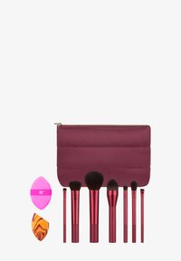 Set di pennelli e spugne per il trucco, con manici metallici rossi e una borsa imbottita color borgogna. Include diverse forme e dimensioni di pennelli.