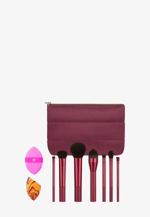 Ensemble de pinceaux et éponges de maquillage, avec des poignées métalliques rouges et un sac rembourré bordeaux. Comprend différentes formes et tailles de pinceaux.