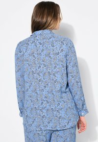Blauwe blouse met paisley-print en lange mouwen, met een zachte textuur, kraag en knoopdetails. Het patroon bevat bloemen- en paisleymotieven.