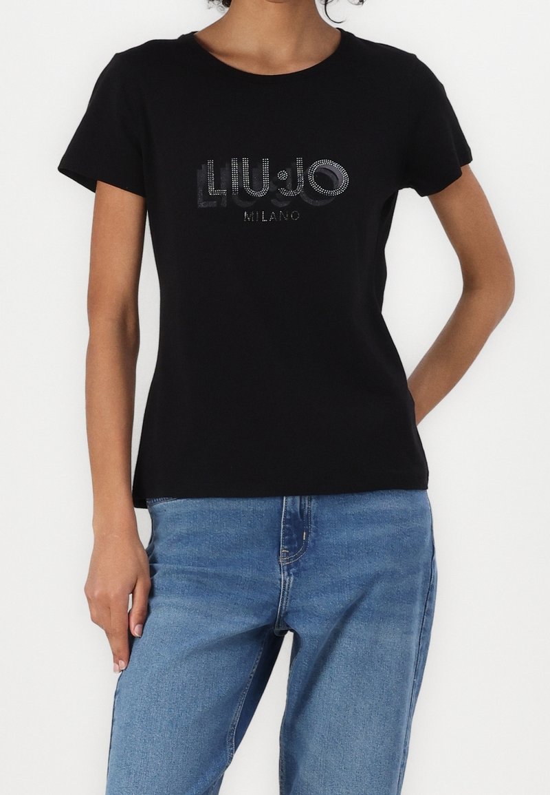 Czarna bawełniana koszulka z okrągłym dekoltem i krótkimi rękawami, ozdobiona srebrnymi cyrkoniami z napisem "LIU.JO MILANO." W połączeniu z niebieskimi dżinsami.