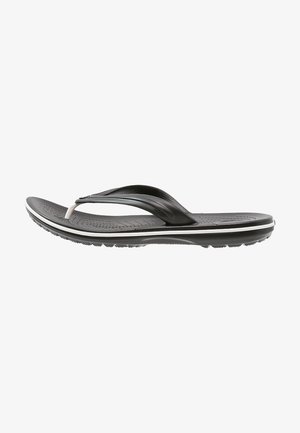 Sandale tongs noire et blanche avec semelle intérieure texturée, bride incurvée et semelle striée pour une meilleure adhérence, vue de côté.