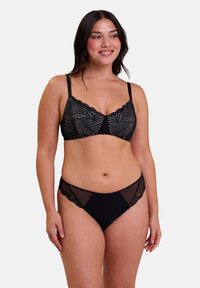 Conjunto de lencería negra que incluye un sujetador de encaje con borde ondulado y detalles de malla, acompañado de una parte de abajo tipo bikini a juego, que destaca por sus intrincados patrones y suaves texturas.