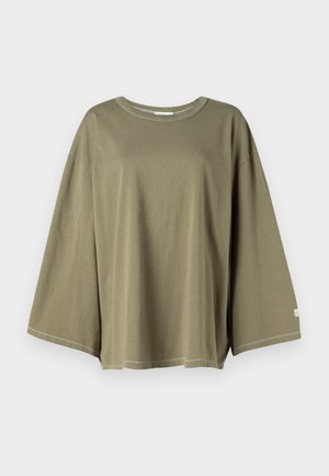 Tricou supradimensionat de culoare verde măslin, fabricat dintr-un material moale. Prezintă un decolteu rotund și mâneci cu um�ăr lăsat, cu cusături contrastante.
