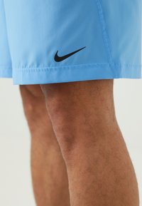 Sinised sportlikud lühikesed püksid, mis on valmistatud kergetest materjalidest. Alumise vasaku ääre peal on must Nike logo ja õmbluste ääres on nähtavad õmblused.