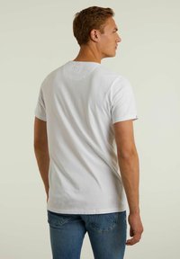 Tricou alb din bumbac cu maneci scurte, guler rotund și un design simplu. Purtați cu blugi blue denim, arătând o croială casual.