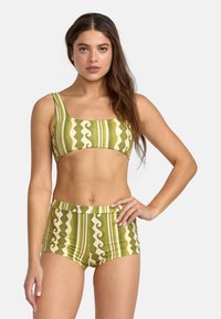 Green patterned bikini top with wide straps and matching high-waisted shorts featuring wavy and striped designs in cream and olive tones.