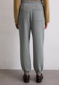 Grijze joggingsbroek gemaakt van zachte stof, met een taps toelopende pijp, elastische tailleband en een achterzak met subtiele stiksels.