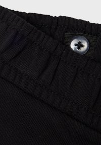 Black knitted fabric waistband with a textured top edge and a blue button with a floral design feature for secure closure.