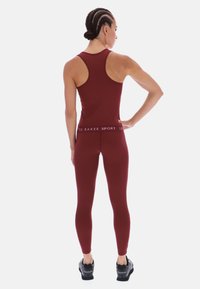 Bordó atlétikai trikó és leggings szett, rugalmas anyagból, sima tapintású felülettel. Márkázott derékpánttal �és atlétikai lábbelivel ellátva.