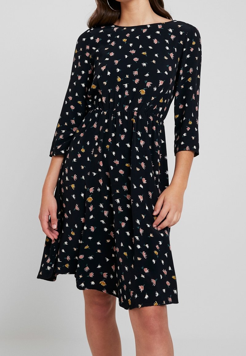 Schwarzes Kleid mit drei Viertelärmeln, das ein florales Muster in Pink, Gelb und Weiß aufweist. Elastischer Taillenbund, knielang, lockere Passform.