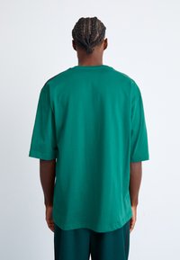 Grøn bomulds t-shirt med afslappet pasform, korte ærmer og rund hals. Materialet er glat med en ensfarvet nuance og minimal detaljering.
