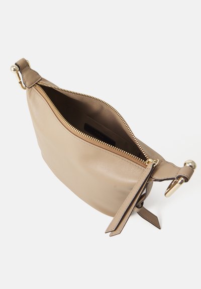 Sac à main en cuir beige avec une ouverture zippée, de forme plate, matériel en ton doré et détail en franges sur le côté. Intérieur doublé en tissu.