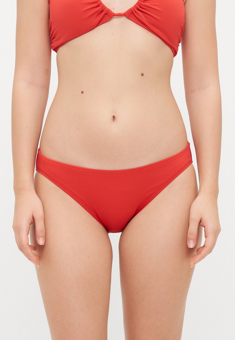 Ensemble de bikini rouge avec un tissu texturé et extensible. Le haut présente un design froncé au centre, tandis que le bas a une forme classique taille mi-haute.