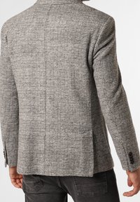 Grå, struktureret blazer i tekstureret stof med et ternet mønster, enkelt slids bagpå og knapper på ærmerne. Skræddersyet pasform med en struktureret design.