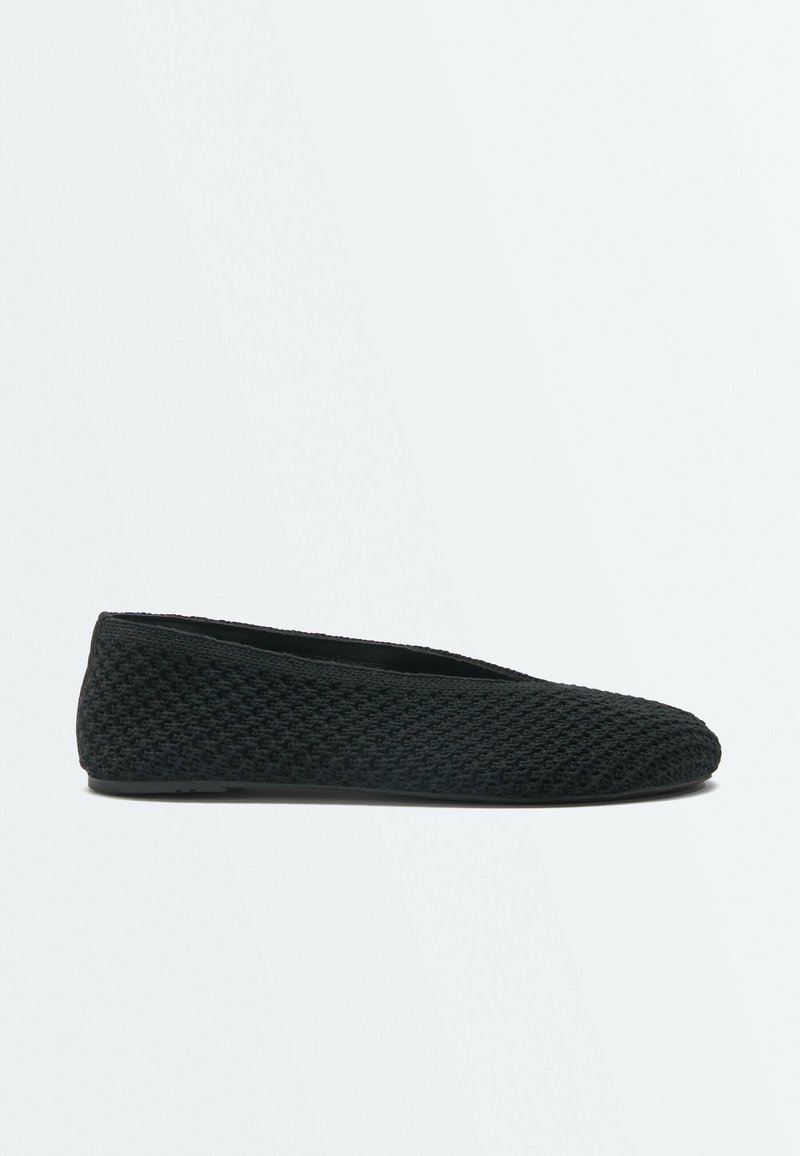 Chaussure de ballet plate noire tissée avec bout arrondi et talon bas, vue de côté sur un fond clair uni.