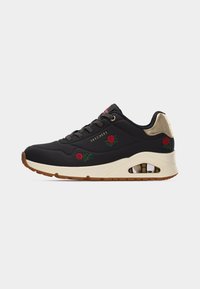 Baskets Skechers noires avec broderie de rose rouge, semelle intermédiaire beige, semelle extérieure marron et accent talon doré métallisé, présentées de profil.