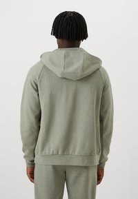 Grå hættetrøje lavet af blødt stof, med en tætsiddende pasform, lange ærmer og en snøre i hætten. Sømløst design med ribbestrikkede manchetter og kant.