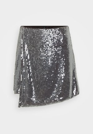 Sudraba spīdīgu mini svārku ar apmetuma dizainu, kuram ir teksturēta virsma un nedaudz asimetriska apakšmala.