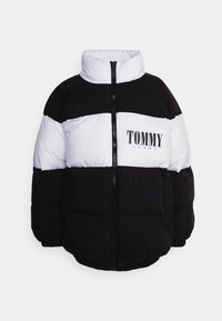 Kurtka puchowa z wysokim kołnierzem, w czarno-białe blokowe wzory kolorystyczne. Na środku znajdują się logo z napisem „TOMMY JEANS”. Zapięcie na zamek błyskawiczny z przodu, pikowana tekstura.