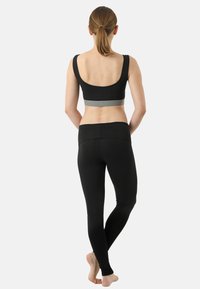 Black athletic bra with a grey band, paired with high-waisted black leggings. Smooth fabric, fitted silhouette, and no visible patterns.
