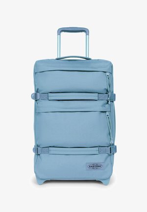 Maleta de tela suave de color azul claro con dos correas de compresión horizontales, asa telescópica y parche con el logo de la marca en la parte delantera inferior derecha.